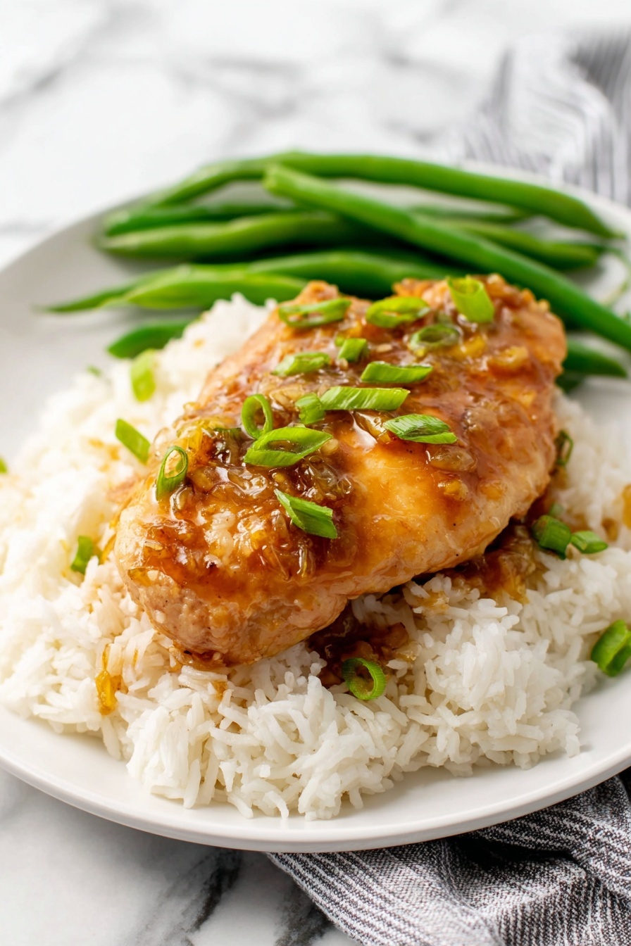 Honey Garlic Chicken - Several pieces of cooked chicken fillets are in a pan, covered by a shiny brown sauce that looks thick and smooth. The chicken is golden brown and tender with small green onion pieces scattered on top. The sauce pools around the chicken, creating a glossy layer that highlights the texture of the meat underneath. The pan shows some browning marks from cooking. The background is a white marbled texture. Photo taken with an iphone --ar 2:3 --v 7