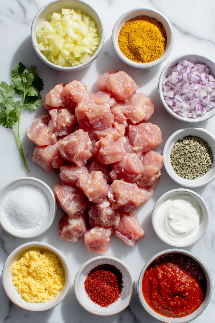 Flat lay of raw chicken thighs cut into cubes arranged neatly, a small mound of finely grated yellow onion, a small pile of peeled and grated fresh ginger, a small heap of minced garlic cloves, a neat stack of mixed ground spices in a small white ceramic bowl showcasing assorted warm reds and browns, a small white bowl filled with smooth bright red tomato puree, a small white bowl with creamy plain Greek yogurt, a small white bowl holding fresh heavy cream, a small white bowl containing fine white tapioca starch powder, a small white bowl filled with dried fenugreek leaves, a few fresh green cilantro sprigs artfully placed nearby, and a small white bowl with vibrant red cayenne powder, all placed on a clean white marble surface, soft natural light, photo taken with an iPhone, professional food photography style, fresh ingredients, white ceramic bowls, no bottles, no duplicates, no utensils, no packaging --ar 2:3 --v 7 --p m7354615311229779997