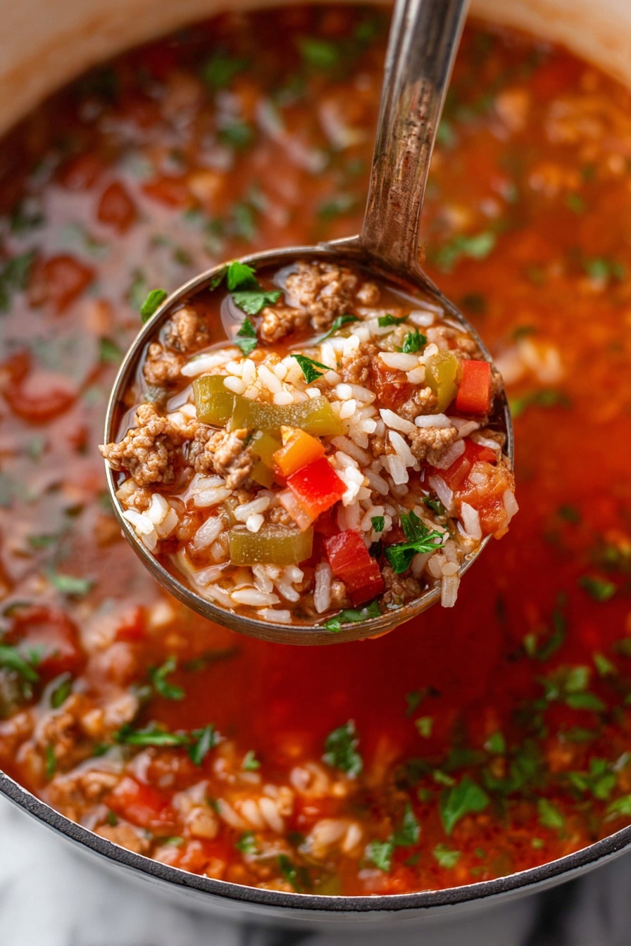 A white bowl filled with a thick stew made of red tomato chunks, brown cooked ground meat, white cooked rice, and small green bell pepper pieces, all mixed in a rich reddish broth. The stew is garnished with small green parsley leaves scattered on top. A silver spoon is scooping up a mix of rice, meat, tomato, and green pepper from the bowl. The bowl rests on a matching white plate, both placed on a white marbled surface. Photo taken with an iphone --ar 2:3 --v 7