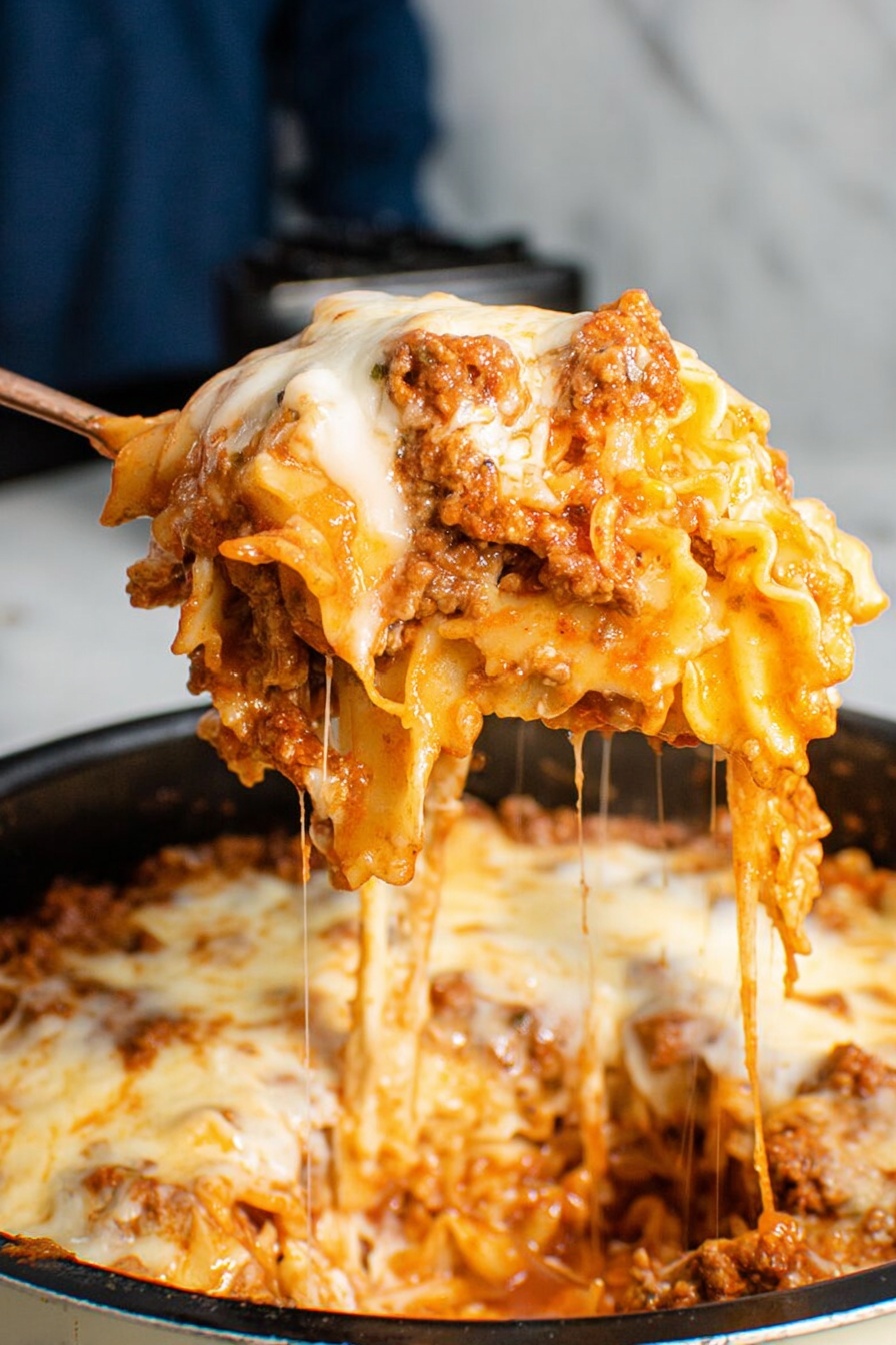A large spoon holds up a cheesy pasta dish with visible layers of wavy-edged pasta, rich meat sauce, and melted white cheese stretching in strings down to the pot below. The top layer is covered with smooth, melted white cheese, slightly browned in spots, sitting over a thick layer of orange-red sauce blending with ground meat and pasta. The pasta beneath is a golden yellow, soaked with sauce and cheese, showing rough edges and folded shapes. The background features a blurred person in blue and dark objects, all atop a white marbled surface. Photo taken with an iphone --ar 2:3 --v 7