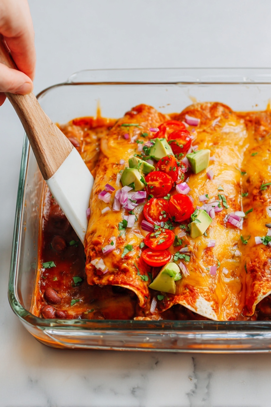 The image shows a glass baking dish filled with two rolled enchiladas topped with melted orange cheese. The enchiladas are filled with a red sauce and some visible beans. On top of the cheese, slices of bright red cherry tomatoes, small chunks of green avocado, and tiny bits of chopped purple onion and green herbs are scattered. A woman's hand is using a wooden spatula with a white handle to lift one enchilada. The background and surface have a white marbled texture. photo taken with an iphone --ar 2:3 --v 7