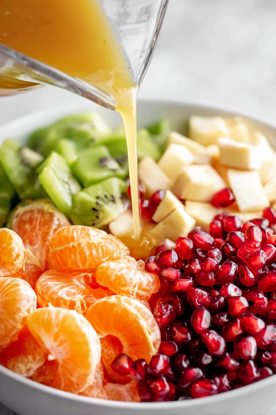 A wooden spoon holds a colorful mix of fruit pieces above a large white bowl filled with the same fruit salad. The fruit pieces include red strawberry slices, bright orange mandarin segments, green kiwi chunks, white apple or pear pieces, and small shiny red pomegranate seeds. The fruits show various textured surfaces: the smooth, juicy orange and strawberry, the slightly grainy kiwi with its small black seeds, and the firm white fruit chunks. The bowl and spoon rest on a white marbled surface. Photo taken with an iphone --ar 2:3 --v 7