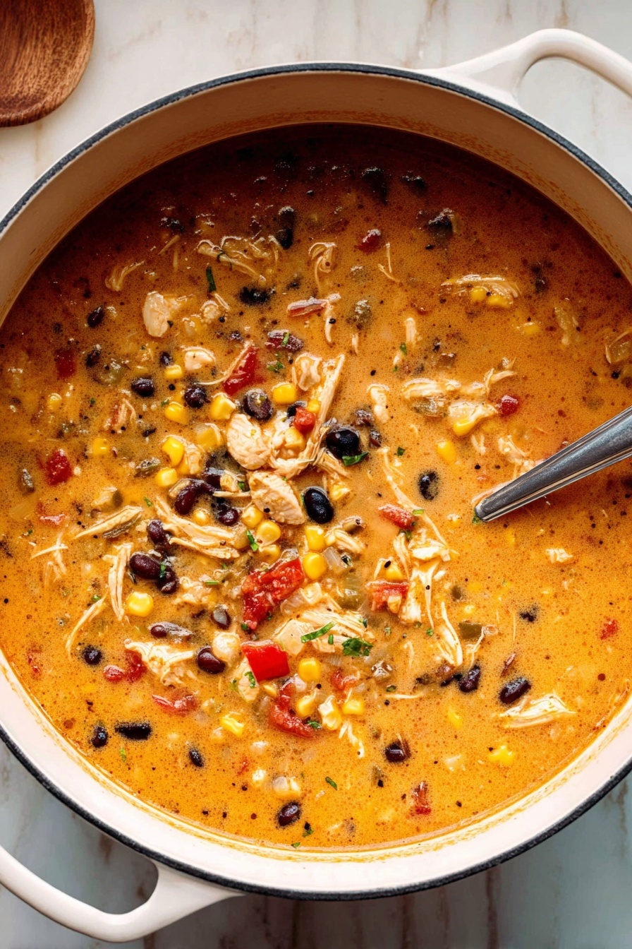 A white pot filled with a thick, creamy orange soup mixed with shredded light brown chicken, kernels of yellow and white corn, small black beans, and small pieces of red and green peppers scattered throughout. A metal spoon rests inside the pot, partially submerged in the soup. The pot is placed on a white marbled surface, and the soup looks hearty and full of texture with a mix of smooth and chunky ingredients. photo taken with an iphone --ar 2:3 --v 7