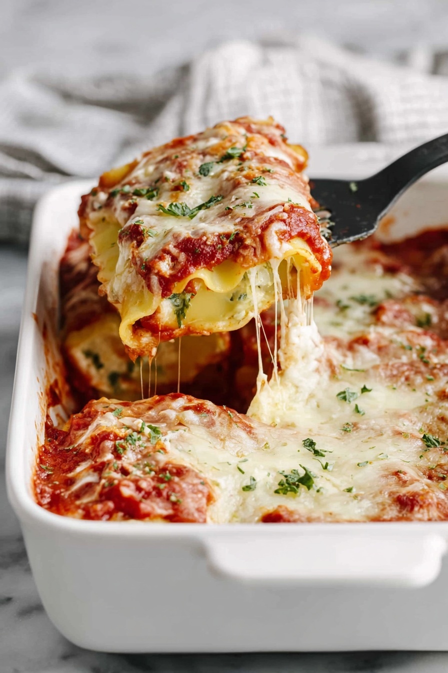 A white baking dish with layers of rolled pasta filled with a creamy white mixture, covered in red tomato sauce and melted white cheese. The top layer shows the pasta roll and sauce bubbling, sprinkled with small green herb pieces. A black spatula lifts one pasta roll, showing stretchy melted cheese pulling away. The dish sits on a white marbled surface, and a blurred white and gray cloth is in the background. photo taken with an iphone --ar 2:3 --v 7