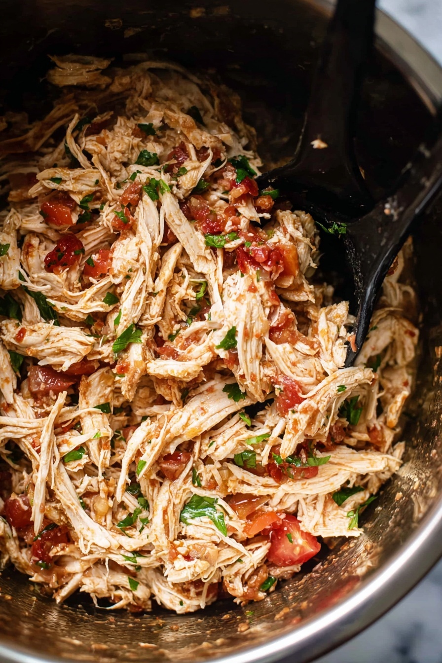 Inside a shiny silver pot filled with shredded light brown chicken mixed with small pieces of red tomato and green parsley, two black spoons rest on the right side, partially submerged in the mixture. The chicken strands look soft and juicy, with a slight shine, while the herbs add a fresh green contrast to the warm colors. The background shows a white marbled texture. photo taken with an iphone --ar 2:3 --v 7