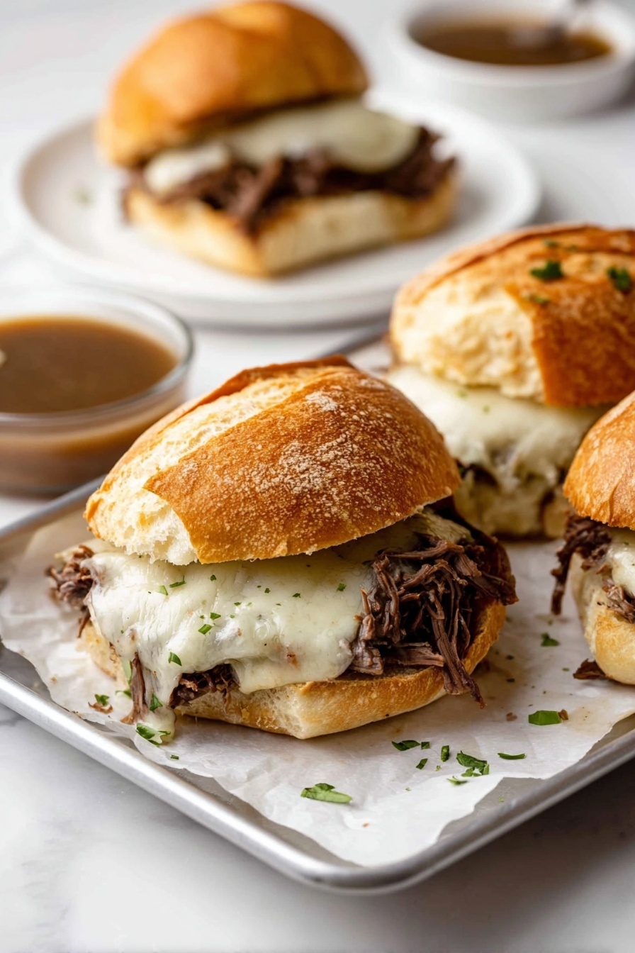 The image shows three sandwiches made with crusty, golden-brown bread rolls, each cut horizontally. Inside the sandwiches, there is a generous layer of shredded dark brown meat topped with melted white cheese, which looks creamy and slightly stringy. Small green herb pieces are sprinkled on the cheese and around the sandwiches on a white paper-lined metal tray. In the background, a white plate holds another sandwich along with a small glass bowl filled with brown gravy. The setting is on a white marbled surface, creating a clean and bright look. Photo taken with an iphone --ar 2:3 --v 7