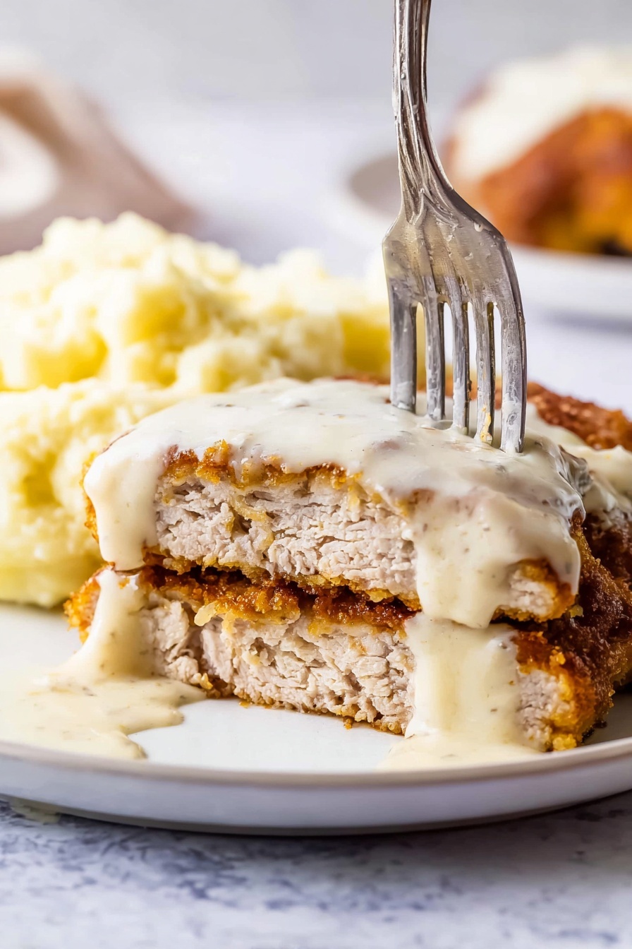 The image shows a close-up of a silver pan filled with thick, creamy white sauce that has small bits of black pepper throughout. A silver spoon scoops some sauce, showing its smooth and rich texture, while the pan edges and handle are visible. The background has a white marbled texture, highlighting the sauce's creamy look. photo taken with an iphone --ar 2:3 --v 7