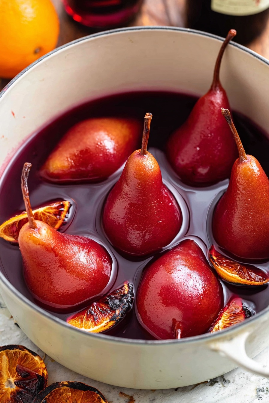 The image shows a white pot filled with six whole red poached pears with their brown stems still attached, floating in deep red liquid, likely wine or syrup. Scattered around the pears are several dark orange slices with a slightly charred look. The pot sits on a surface with white marbled texture, and the background shows a blurred bottle and a hint of an orange in the corner. The pears have a smooth, shiny texture, and the liquid looks thick and rich. Photo taken with an iphone --ar 2:3 --v 7