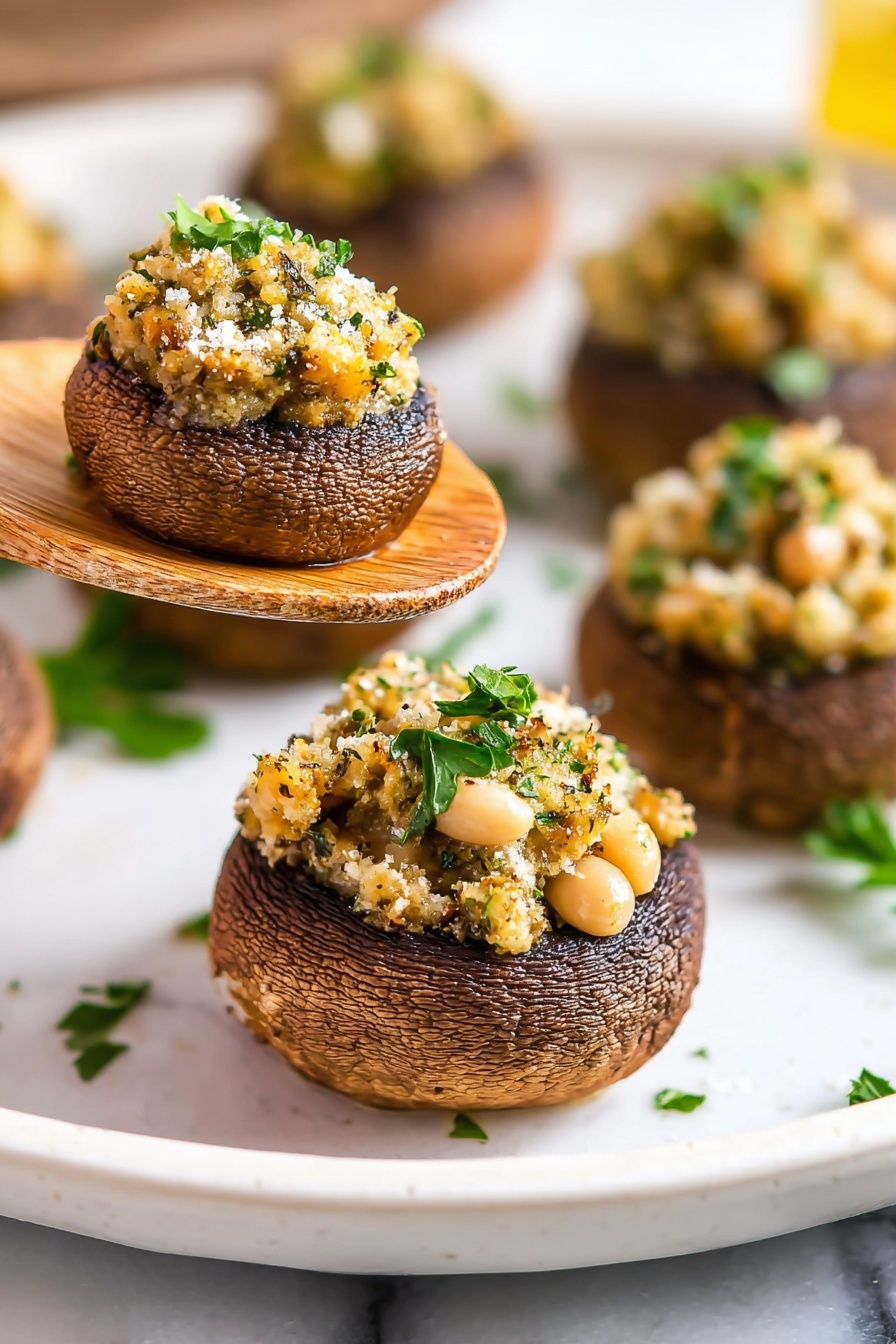 The image shows a close-up of several stuffed mushrooms on a white plate placed on a white marbled surface. Each mushroom has two layers: the bottom layer is a dark brown roasted mushroom cap with a slightly wrinkled texture, and the top layer is a golden-brown stuffing filled with small white beans, herbs, and a sprinkle of fresh green parsley, giving it a crumbly and textured look. One stuffed mushroom is held above the plate on a wooden spatula, highlighting the round shape and detailed textures of the stuffing and mushroom cap. Photo taken with an iphone --ar 2:3 --v 7